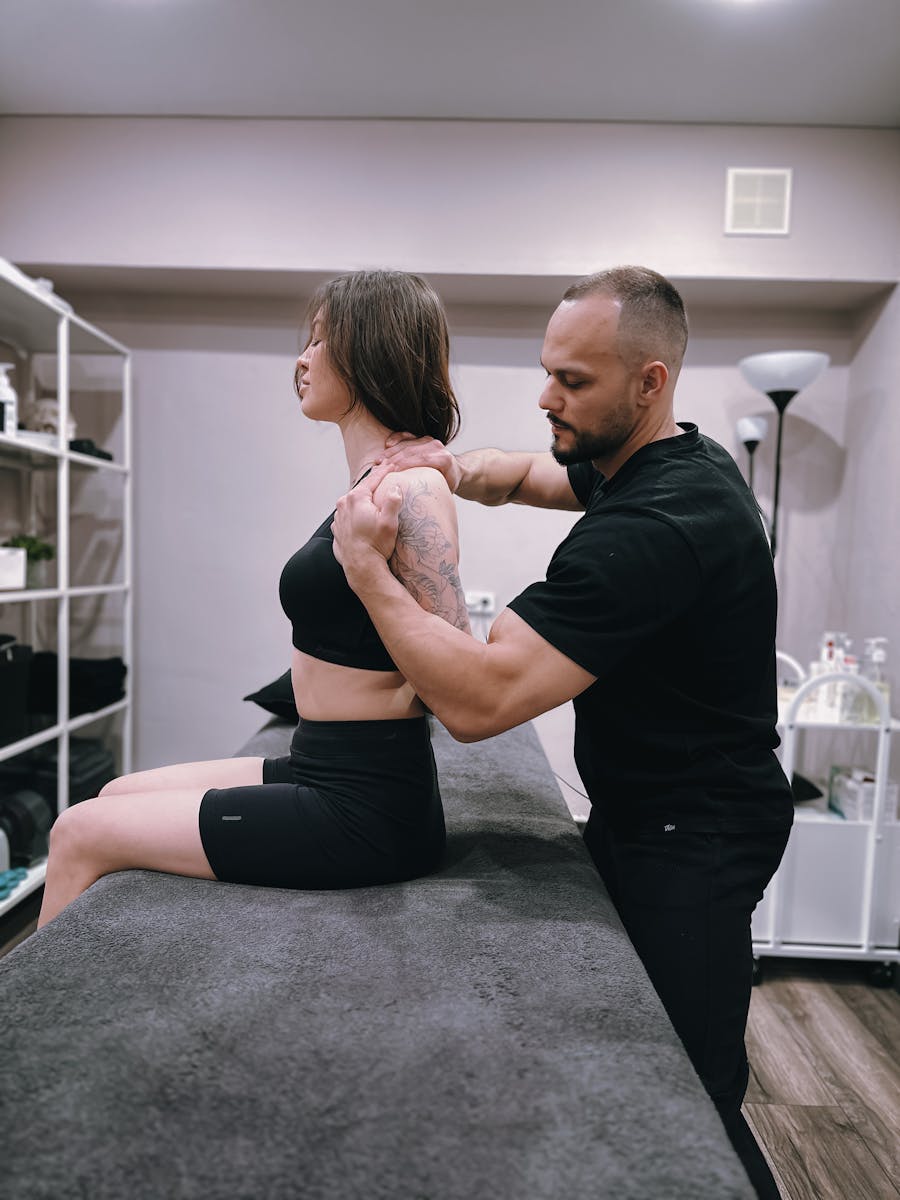Chiropractor adjusting female patient's shoulder in a contemporary clinic setting.