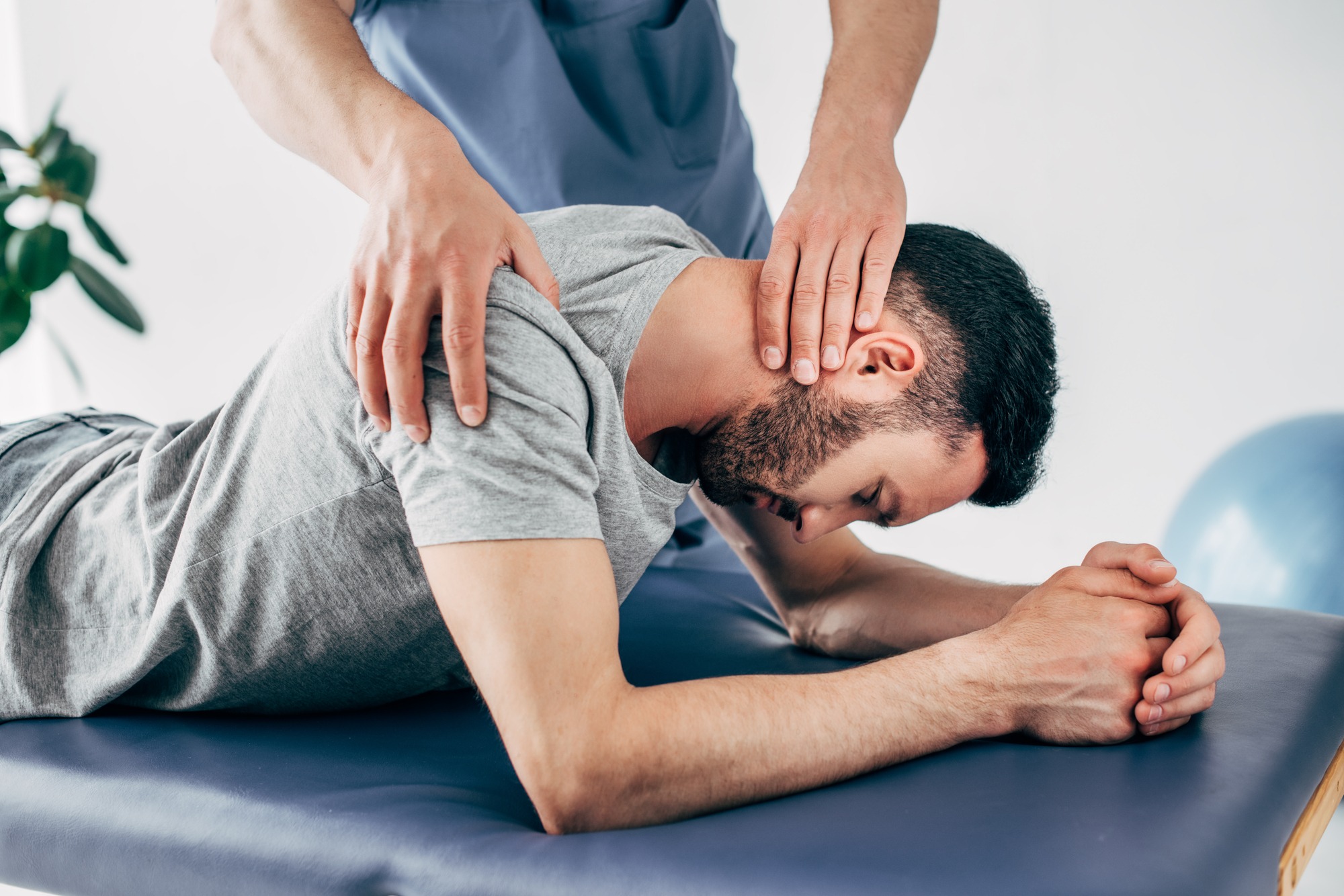 Chiropractor massaging shoulder and neck of man on Massage Table in hospital